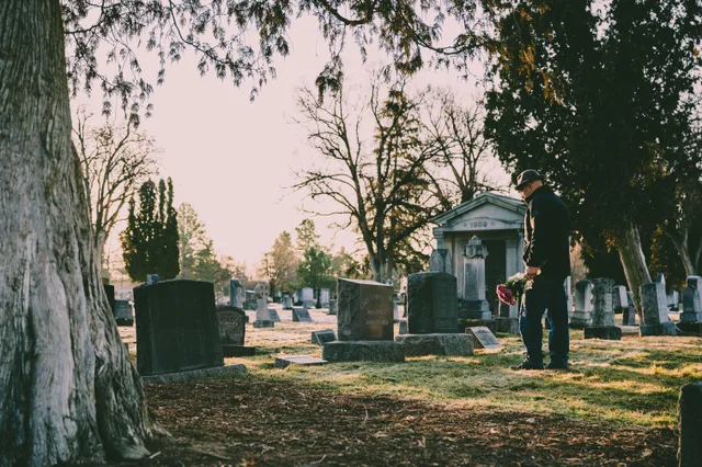 A person stands in a peaceful cemetery holding flowers in remembrance. National Center for Health Statistics death records